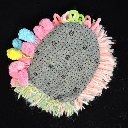 Handmade Blossom Puddle pastel pom-pom crochet coaster back view showing grey non-slip floral pattern base with colorful pom-pom and fringe border on black background – Sylva Garden