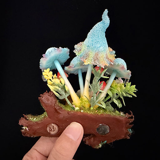 Handmade blue glitter mushroom cluster resin clay magnet held in hand showing full log base with moss flowers and berries, front view – Sylva Garden