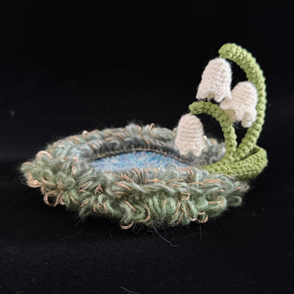 Handmade Dewbell lily of the valley crochet moss coaster side view showing layered green moss texture and white bell bloom stem on black background – Sylva Garden