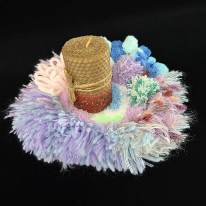 Handmade Dreamy Bog lavender blue pink coral pom-pom crochet coaster styled with beeswax pillar candle on black background, angled side view – Sylva Garden