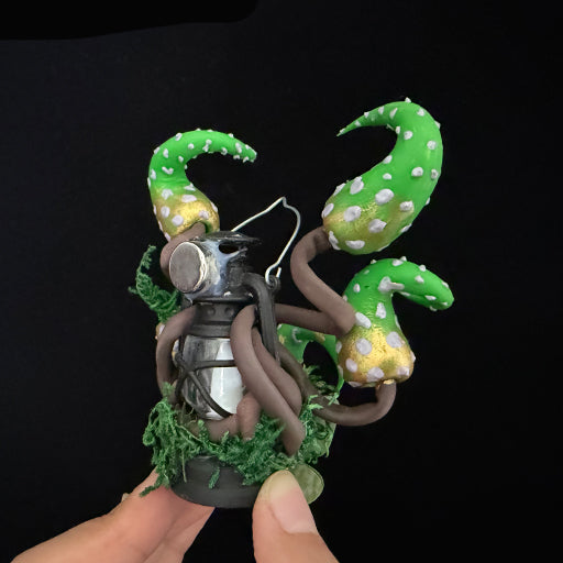 Handmade eldritch tentacle lantern resin clay magnet with green spotted tentacles and moss base, side view on black background – Sylva Garden