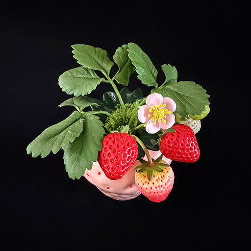 Handmade clay strawberry arrangement overhead view showing red white and green clay strawberries pink blossom and green leaves in pink strawberry-shaped ceramic pot – Sylva Garden