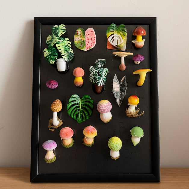 Full collection of handmade resin clay fridge magnets on black display frame, featuring tropical leaves, monstera and mushroom designs – Sylva Garden