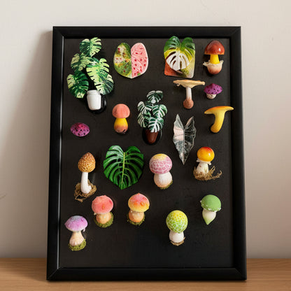 Full collection of handmade resin clay fridge magnets on black display frame, featuring tropical leaves, monstera and mushroom designs – Sylva Garden