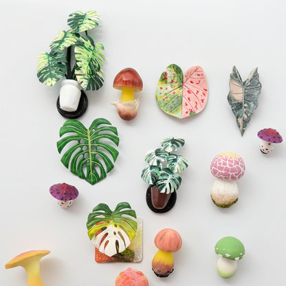 Handmade resin clay fridge magnet collection flatlay on white background, monstera potted plants, mushrooms and tropical leaves – Sylva Garden