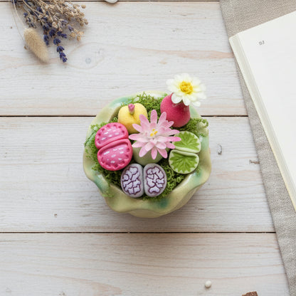 Handmade clay succulent arrangement in green lotus-shaped pot overhead lifestyle view on white wood desk with dried lavender and open book – Sylva Garden