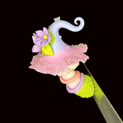 Handmade mauve curl fairy mushroom resin clay magnet with pink ruffled cap purple daisy flowers and white curled tendril held in hand on black background – Sylva Garden