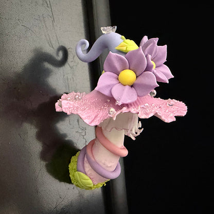 Handmade mauve curl fairy mushroom resin clay magnet with purple flowers and pink ruffled cap attached to metal refrigerator door, lifestyle view – Sylva Garden