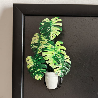Handmade monstera potted plant resin clay fridge magnet in white pot, close-up on black display board – Sylva Garden