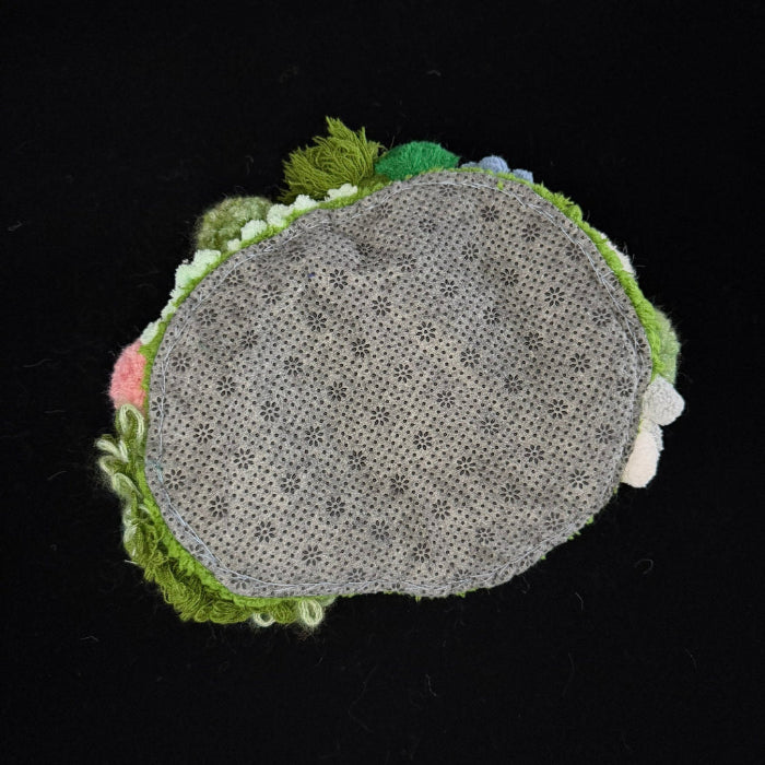 Handmade Moss Wanderer green multi-texture pom-pom crochet coaster back view showing grey floral non-slip fabric base with green pom-pom border on black background – Sylva Garden