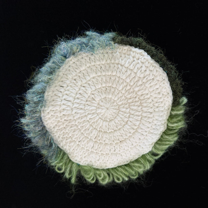 Handmade Pixie Ring red lace mushroom crochet moss coaster back view showing cream white crochet base with blue green moss border on black background – Sylva Garden