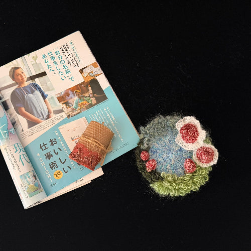 Handmade Pixie Ring red lace mushroom crochet moss coaster styled with Japanese magazine and beeswax candle on black background, lifestyle view – Sylva Garden