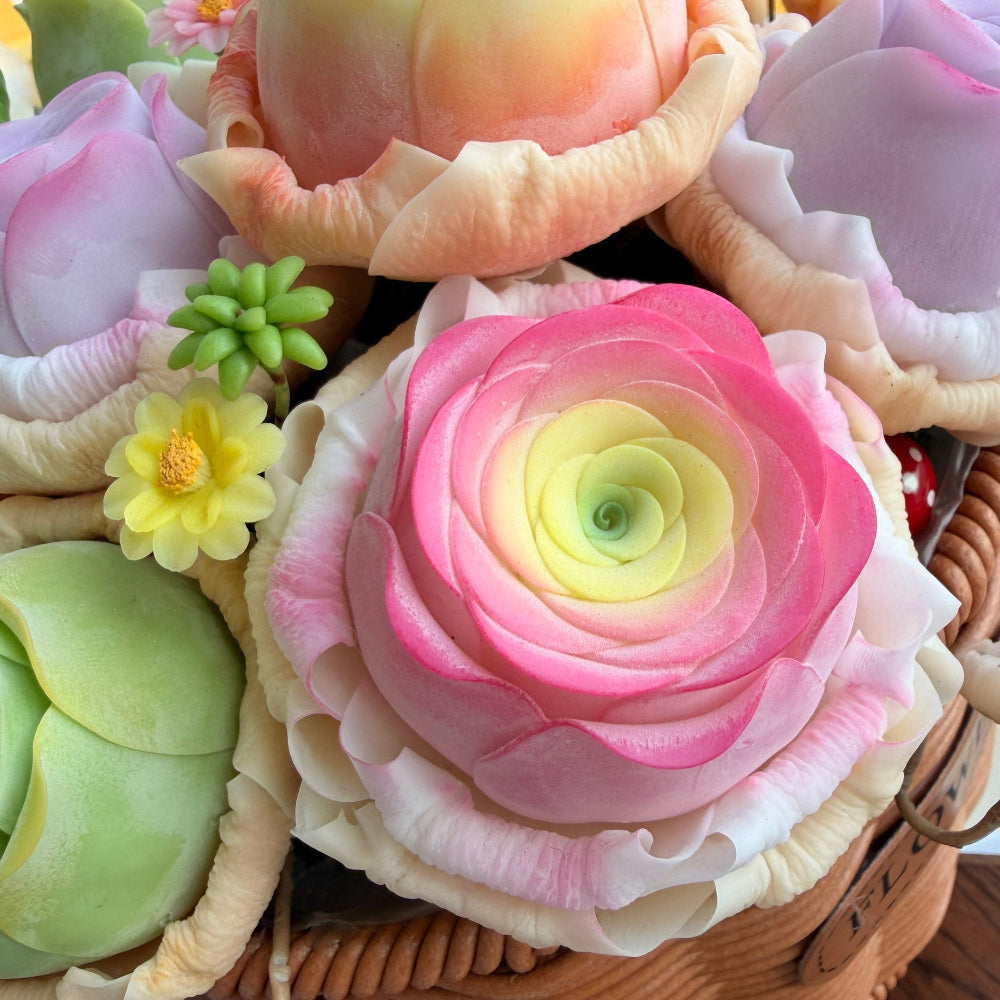 Rose Succulent Carnival handmade clay close-up showing pink gradient ranunculus center with yellow daisy and green succulent rosette detail in woven basket – Sylva Garden