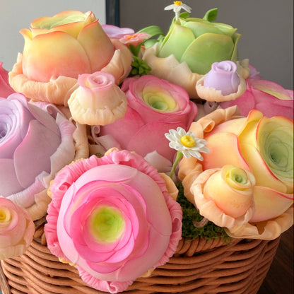 Rose Succulent Carnival handmade clay ranunculus and succulent arrangement side angle view showing pastel pink orange and purple blooms with daisy accents in woven basket – Sylva Garden