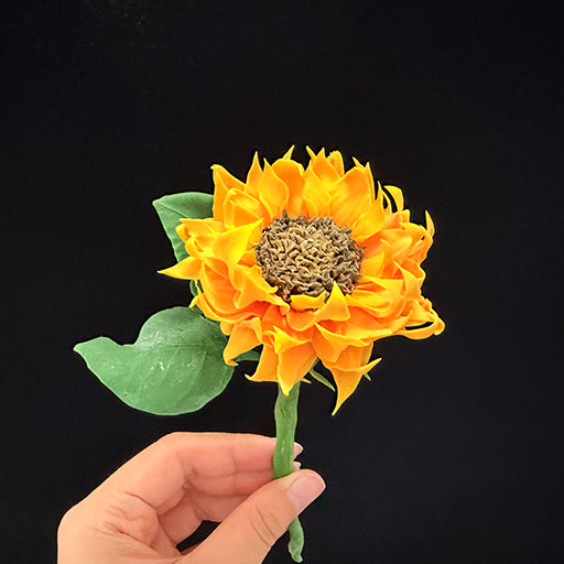 Handmade resin clay yellow sunflower single stem with green leaves held in hand, front view showing layered petals and textured center – Sylva Garden