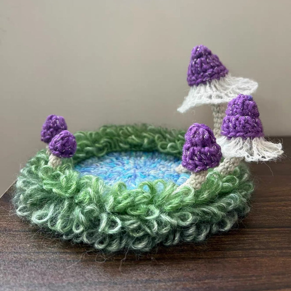 Handmade Violet Veil purple mushroom crochet moss coaster with white lace veil caps and green moss border on wooden table, side view – Sylva Garden
